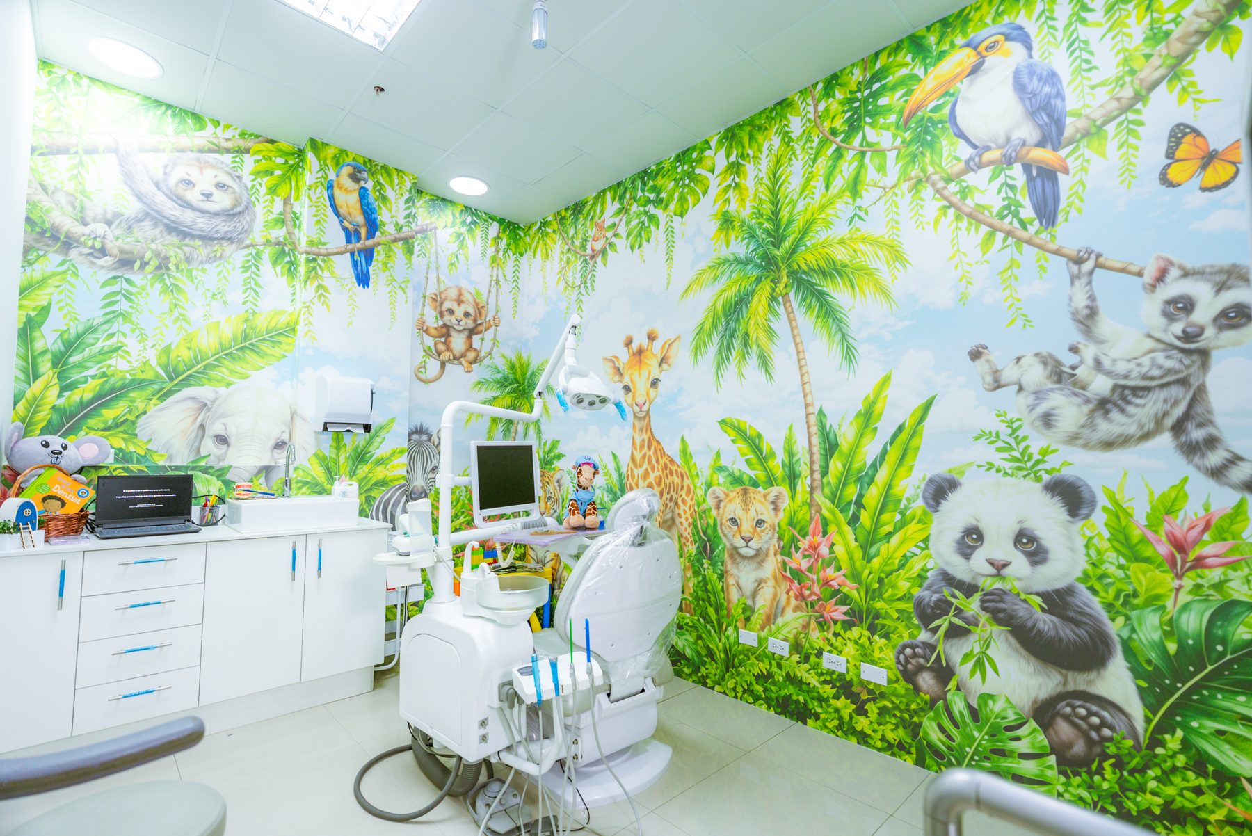 Consultorio infantil de Rubattino con un mural de selva pintado de pared a pared y el sillón dental al centro