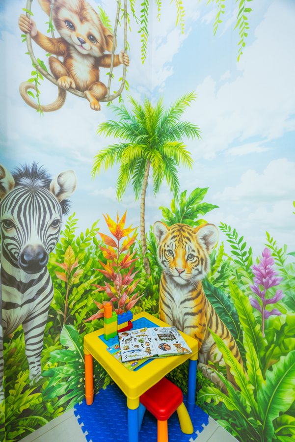 Rincón de juegos con mesita, sillas de colores y libros de animales